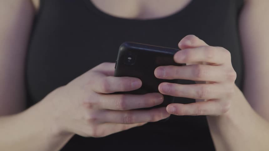 A woman types on a smartphone before raising the phone to her ear