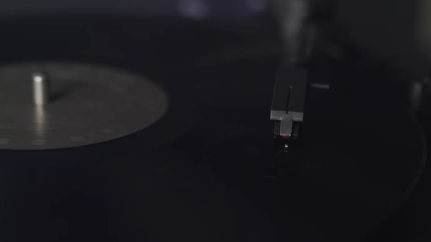 A needle on a record player lowering on to an album