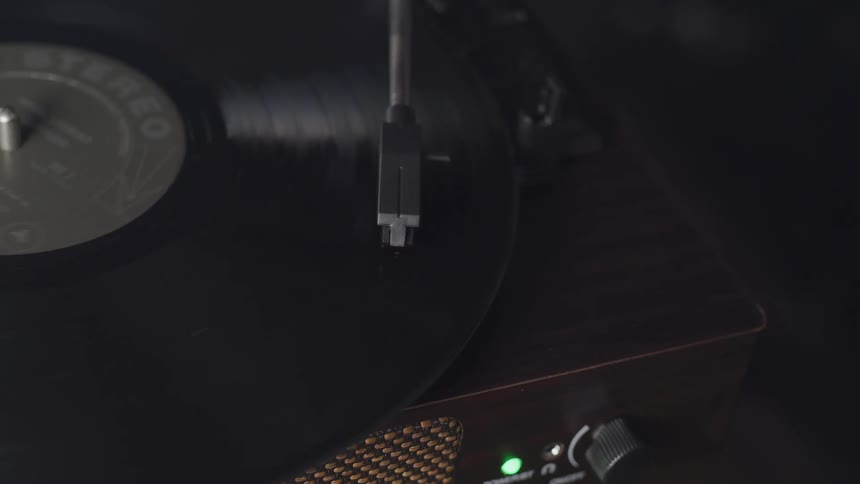 The stylus of a record player lowers itself onto a record and gently glides over it