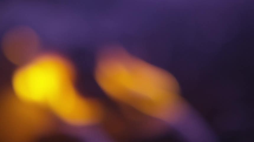 Out of focus yellow flames on a dark violet background