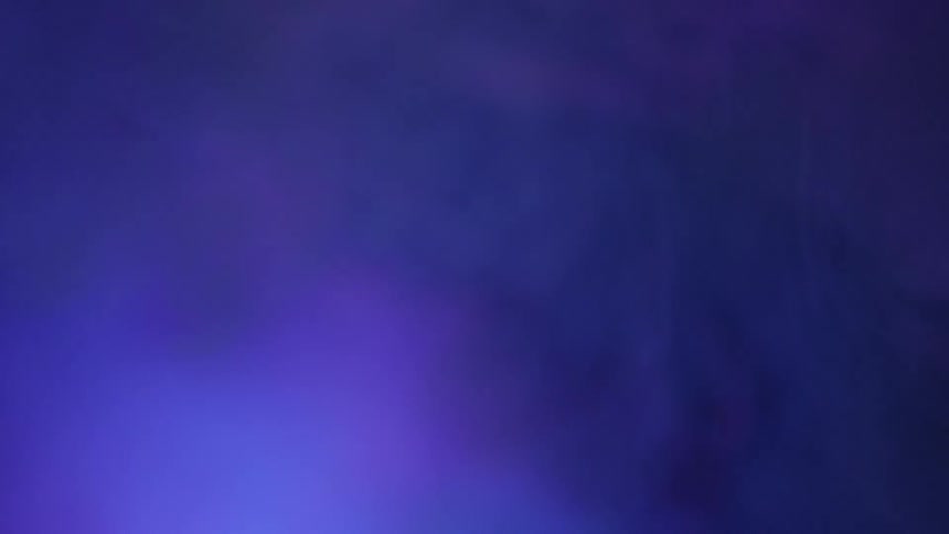 Blue and purple smoke clouds billow up against a dark surface