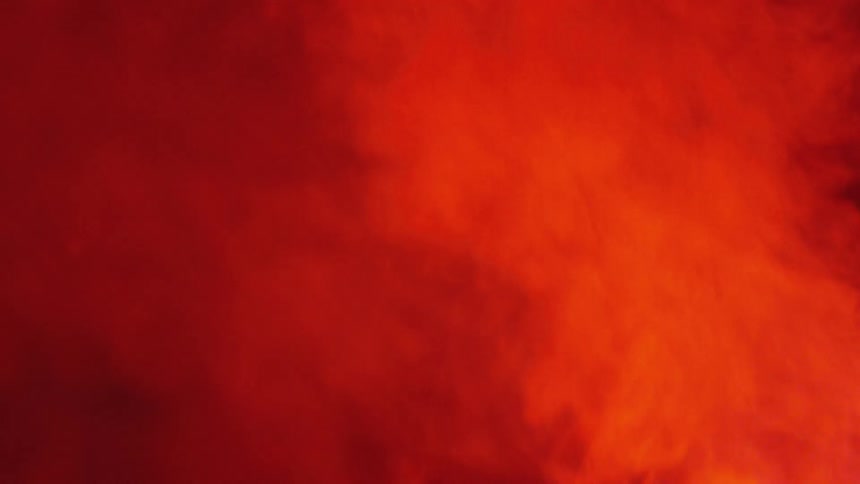 Smoke continues to billow and rise as the light upon it casts a reddish hue