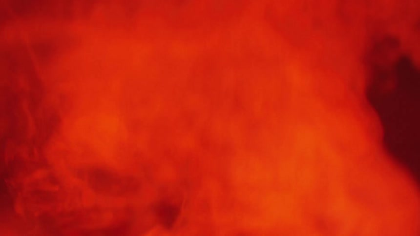 Smoke and flames rise from a fire in the night