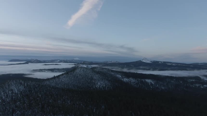An aerial view of a snowy mountain landscape at dawn