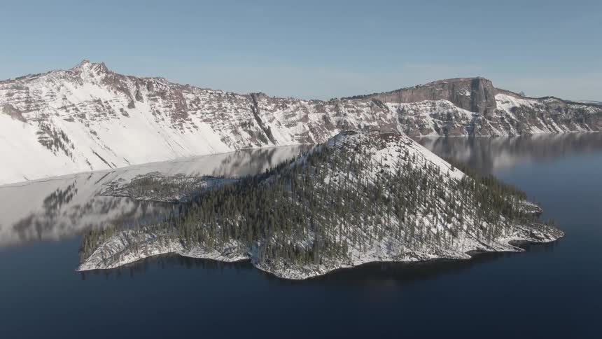 Aerial view of a small island on a lake near the snow covered mountains