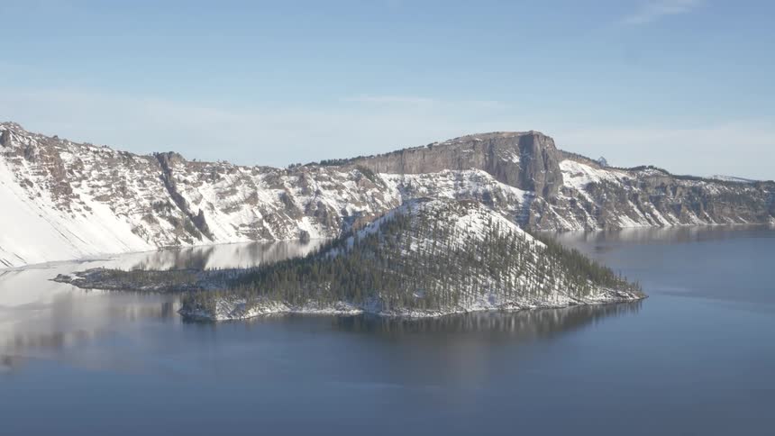 An aerial view of a mountain is displayed by the sea