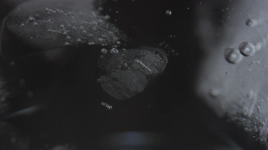 Bubbles float through a liquid in a glass
