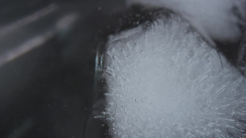 Bubbles rise around ice cubes in a clear liquid