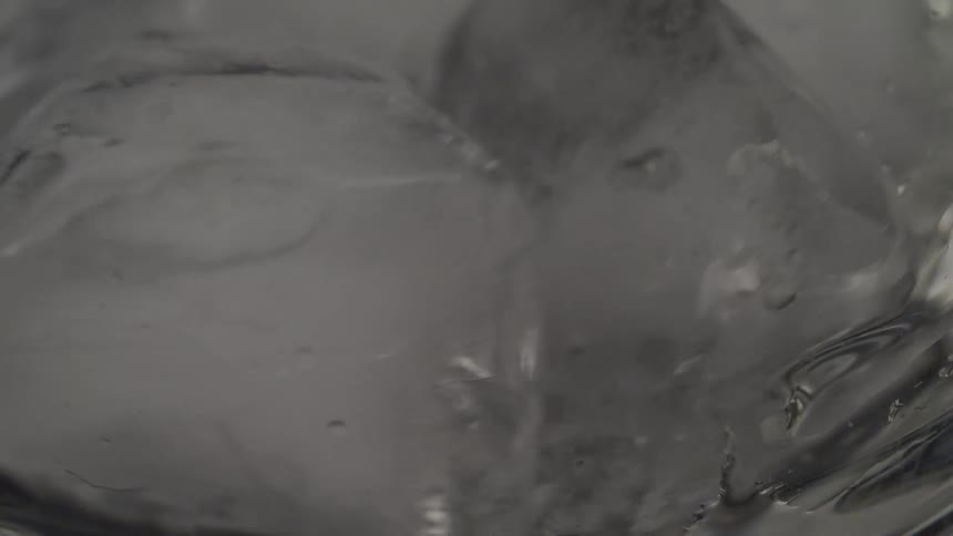 Ice cubes fall into a clear glass