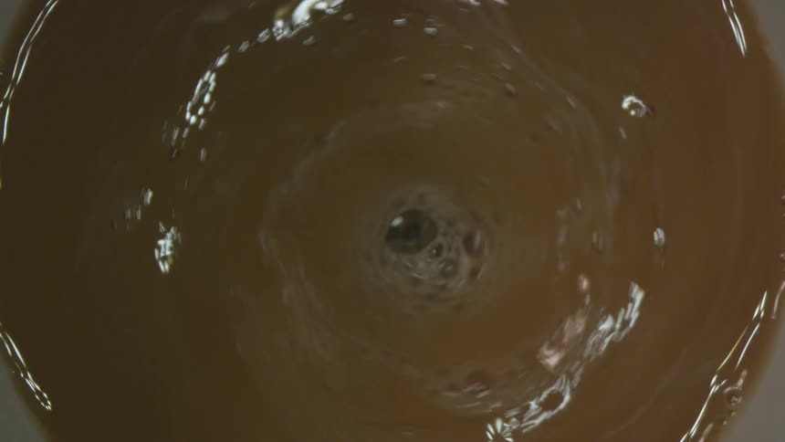 Creamer added to swirling coffee turning it lighter