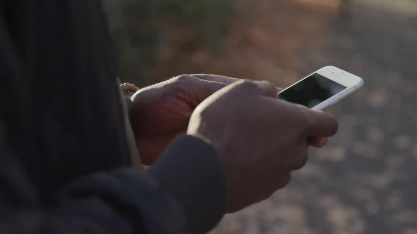 Man typing on his smartphone outdoors at sunset