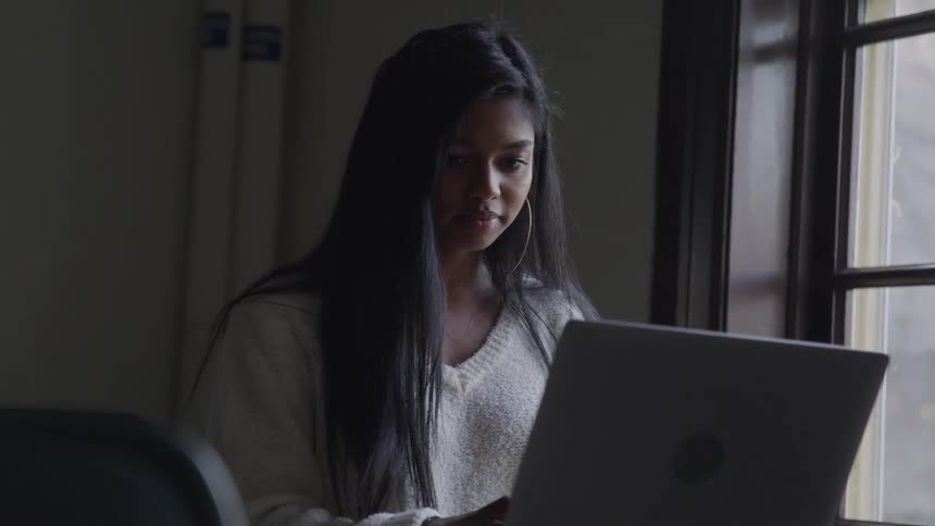 A young woman in an office works on a laptop