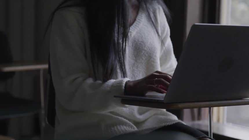 A teenage girl works on a laptop in a classroom