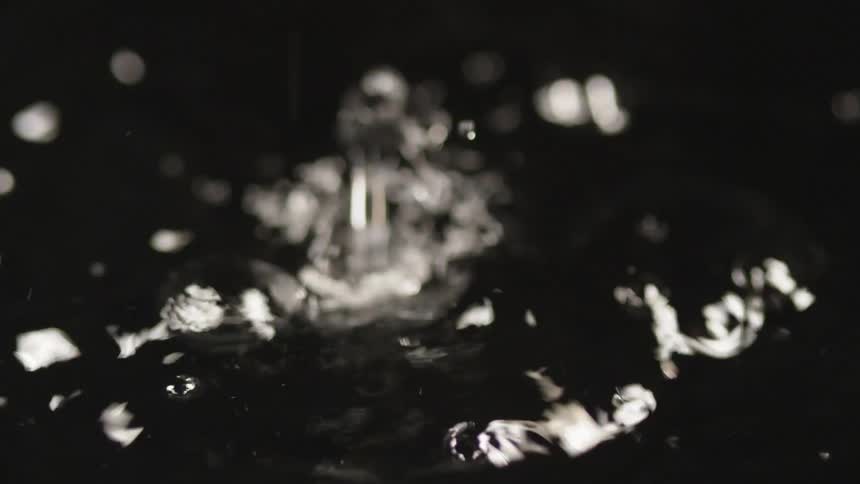 Water droplets dribble and drop as they splash and splatter against the surface of the liquid