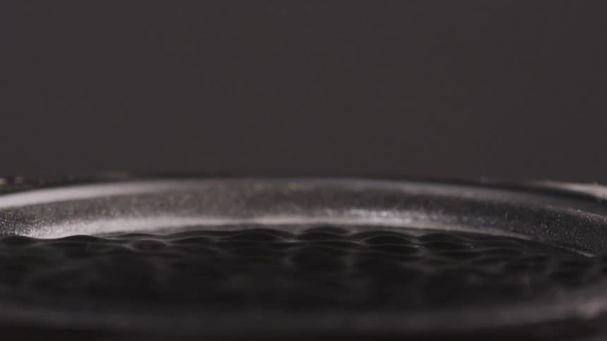 Boiling water bubbles up to the surface of a black pot