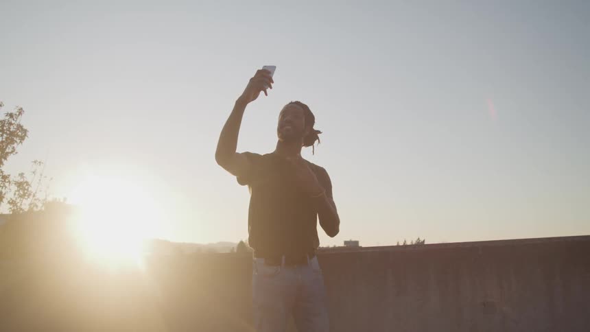 Black man smiles and takes a selfie at sunset