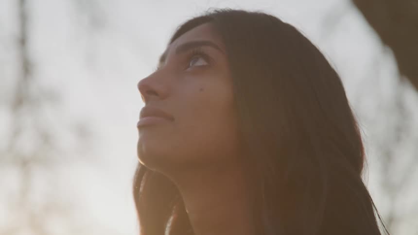 A woman is standing outdoors at dusk