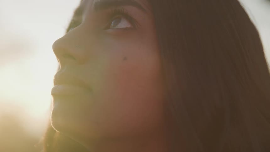 A teenager girl outside looks up towards the sky