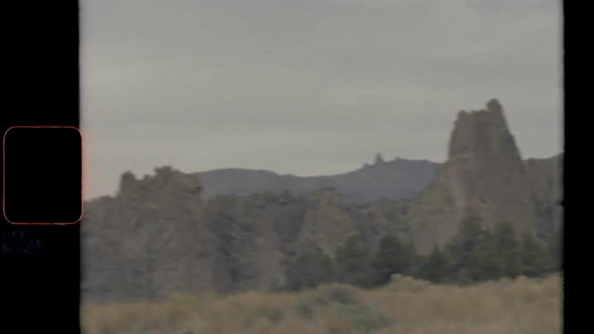 Vintage footage of a landscape with a grassland and cliffs
