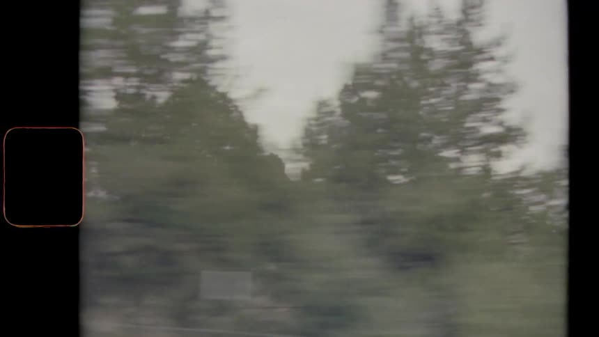 Vintage footage of a cliff behind trees in a grassland area