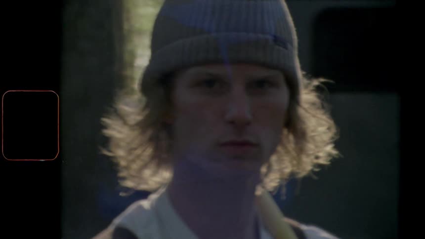 Man with a grey beanie and long hair stares at the camera