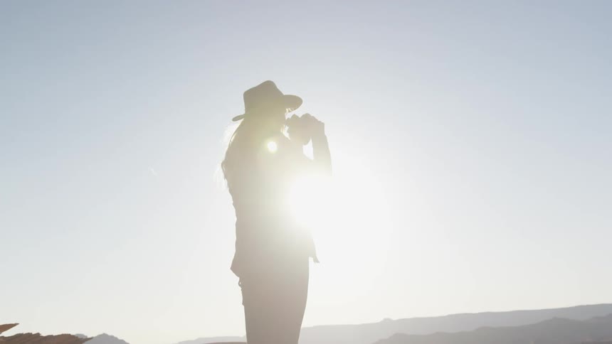 A woman raises binoculars to her eyes and looks at the landscape