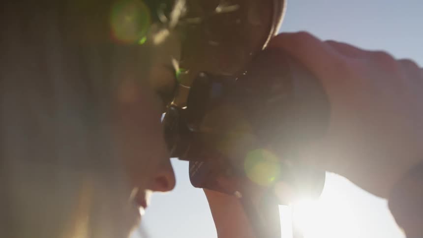 A woman is looking around with her binoculars