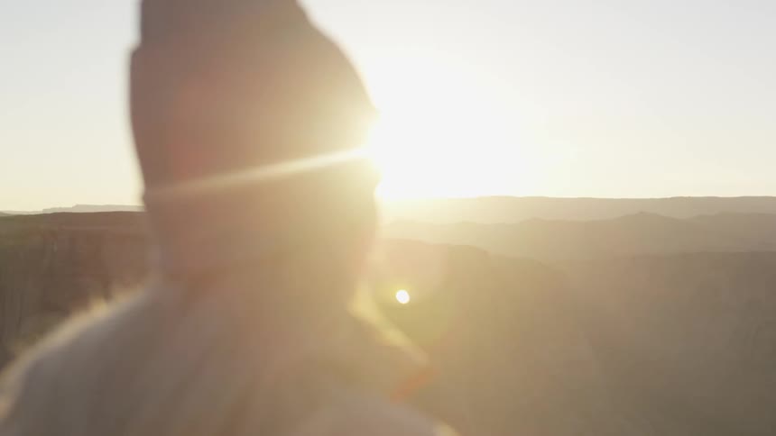 A woman stands and looks out at canyons