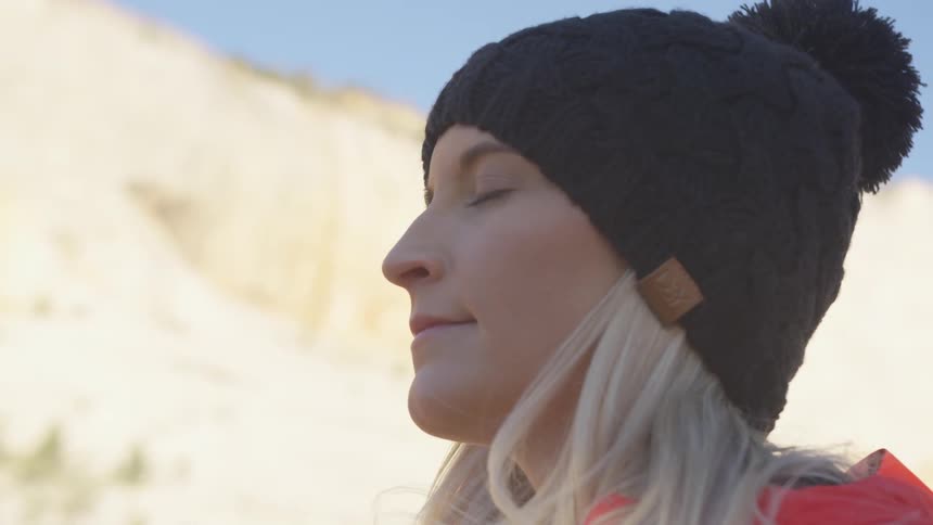 A woman is hiking outdoors while wearing a hat