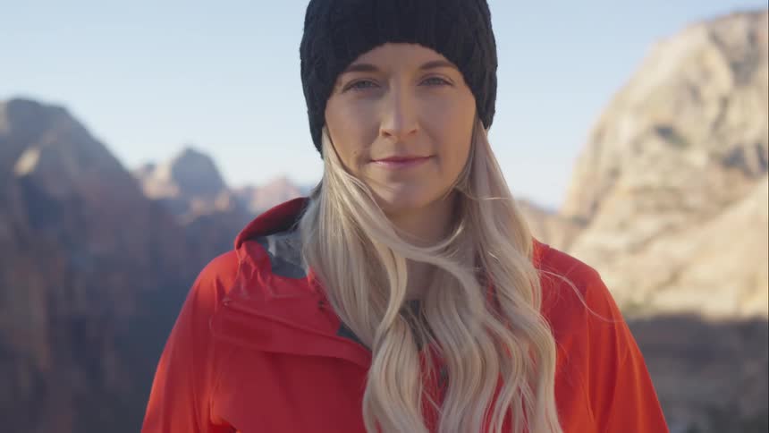Woman looks up from ground standing with mountains at her back