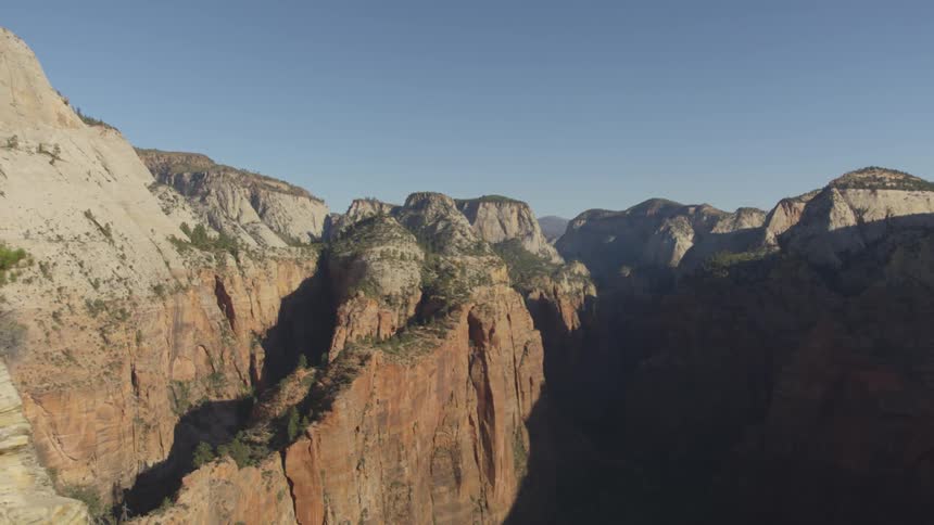 A canyon with trees and cliffs with the sky and clouds in the background