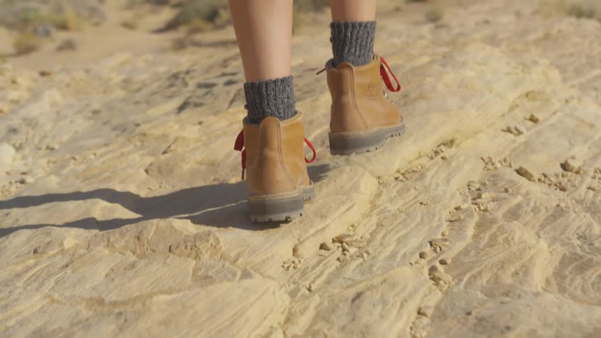 A woman is hiking outdoors while wearing boots