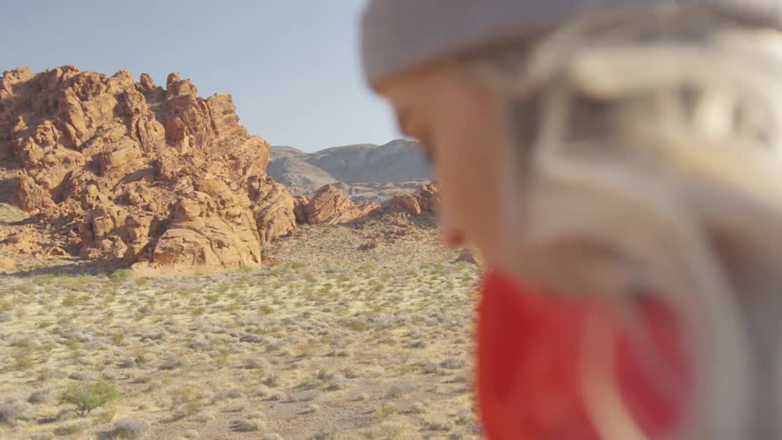 Woman stand above desert bordering mountains
