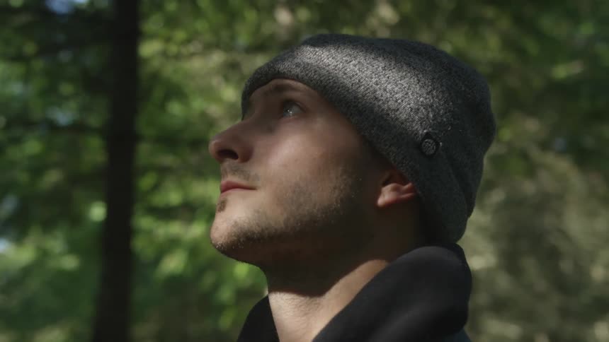 A man is standing outdoors in a forest area