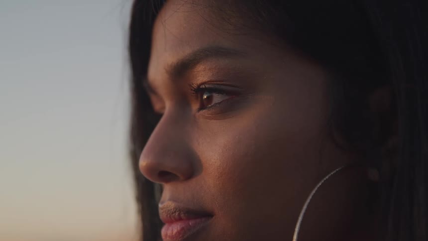 A woman with hoop earrings is posing for a portrait outside