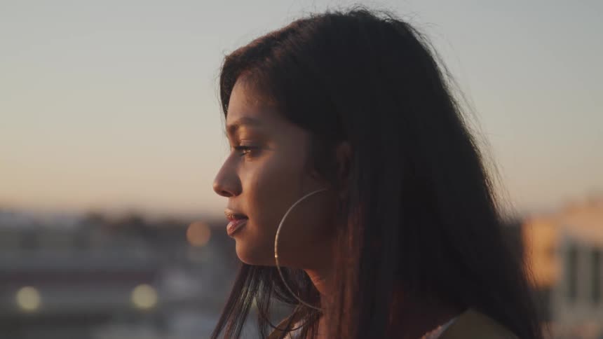 A woman is standing in a city at dusk