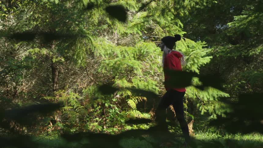 Woman walks through shadows of trees across mowed grass