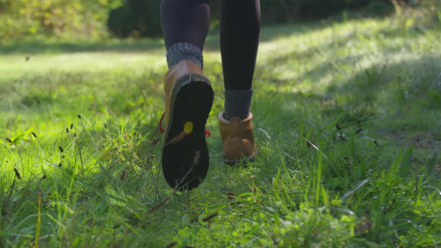 Close up of a womans boots while walking on green grass