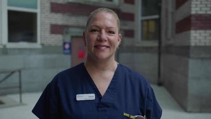 A woman nurse with blue scrubs looking up and smiling