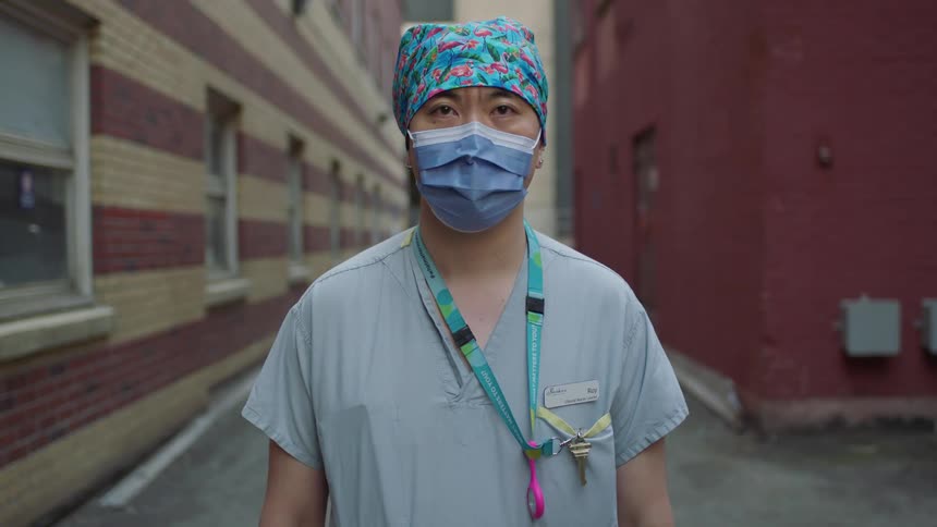 A man is wearing a mask and scrubs while standing outdoors