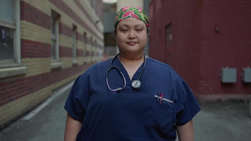 A nurse stands outside and looks ahead