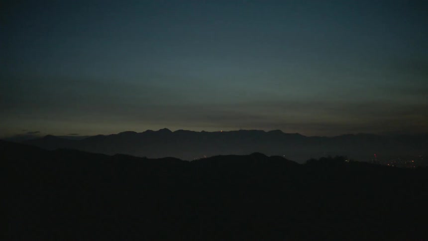 A dark mountain range has the sun setting in the distance