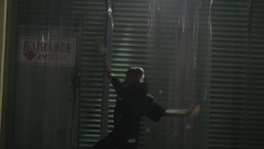 A woman wearing headphones dances outside at night