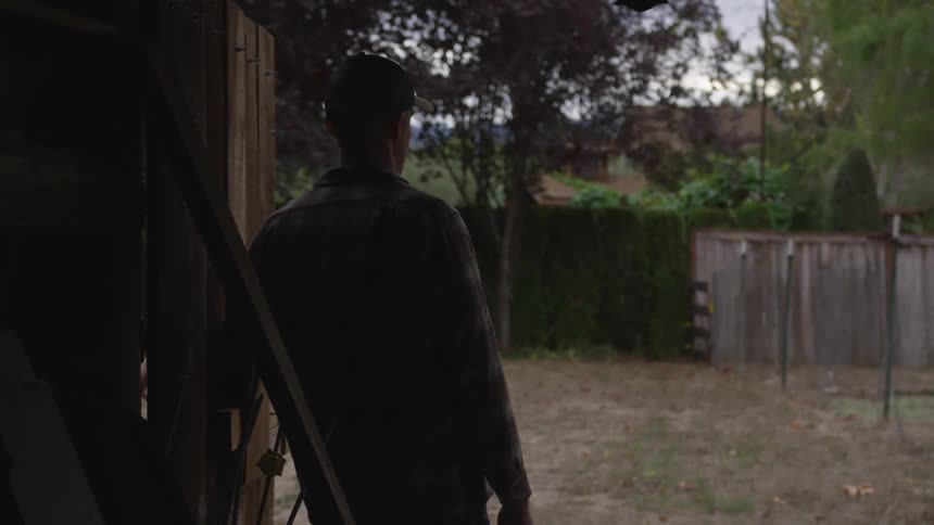 A man stands in his back yard and looks out