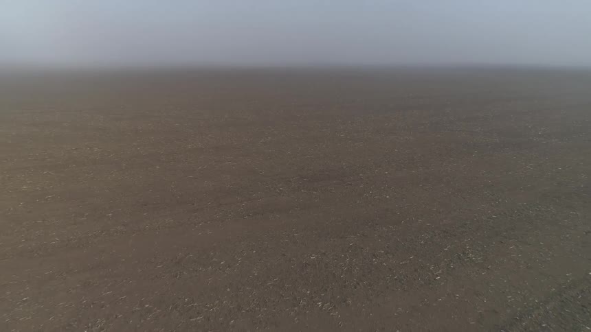 A vast but barren field under thick fog during the day