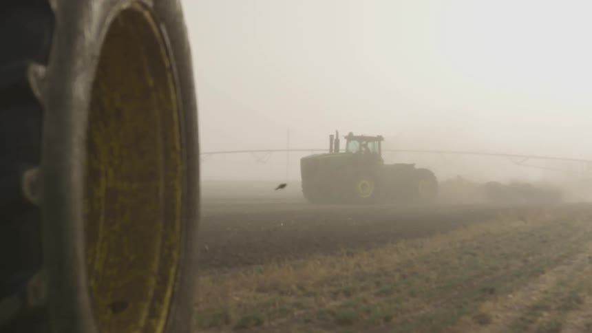 A tractor drives on the farm on a foggy day