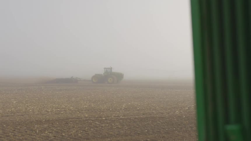 A tractor pulling a plow on a rural dirt field