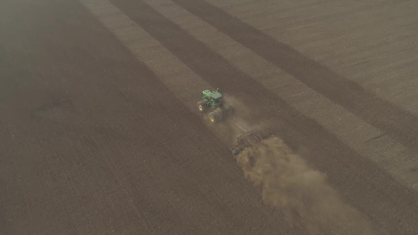 An aerial view of a tractor plowing a dirt field