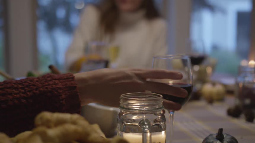 A person grabs for their wine glass at a home dinner table