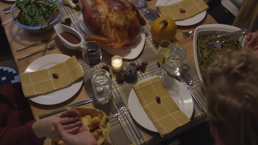 People join hands around the dinner table as a roasted turkey sits on the table